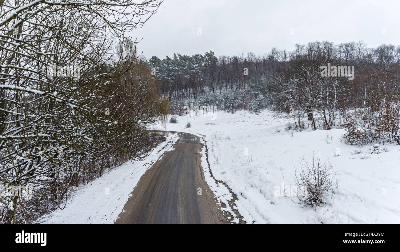 Vista aerea sulla strada e la foresta in inverno. Paesaggio naturale invernale dall'aria. Foresta sotto la neve un inverno. Foto Stock