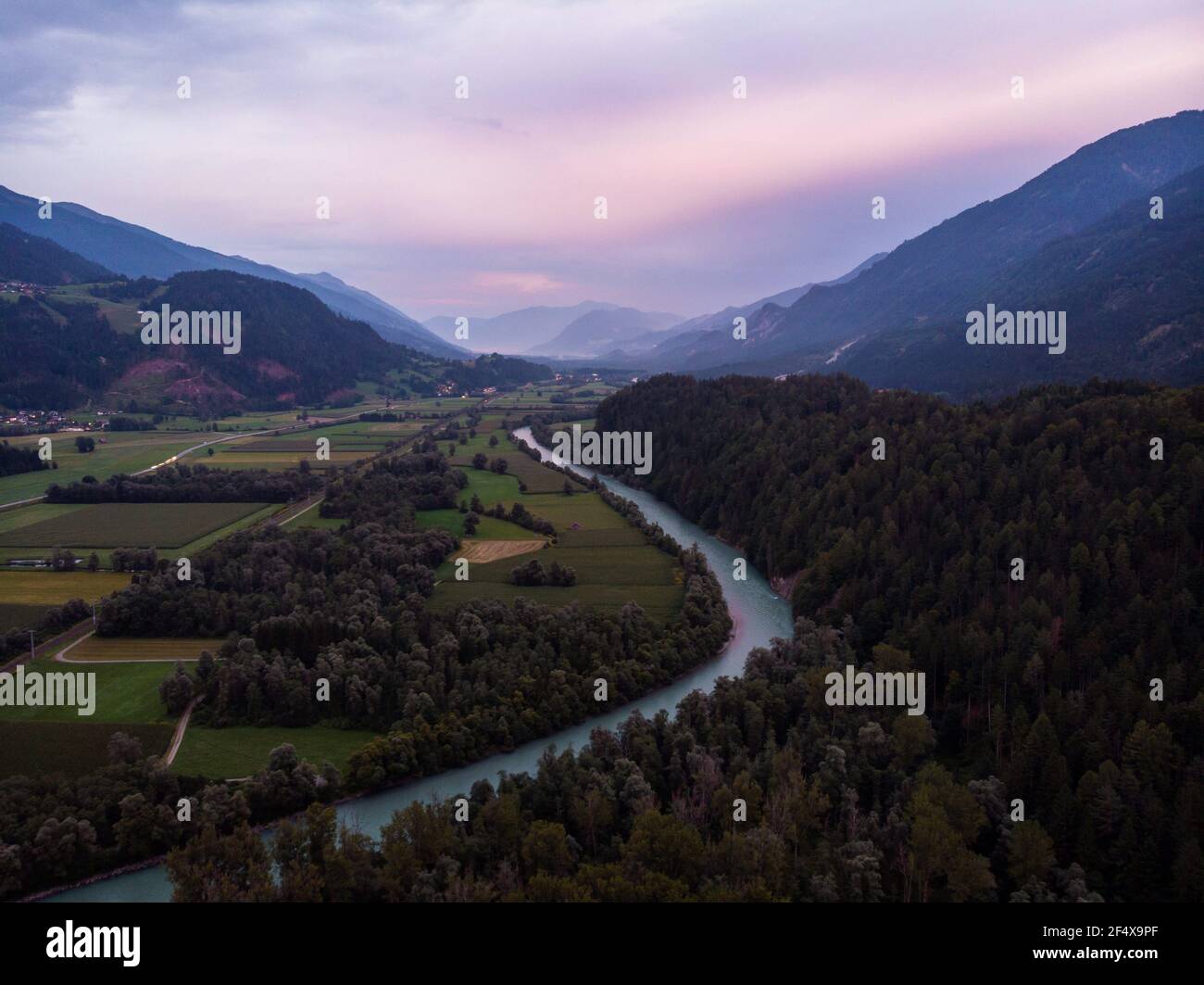 Vista panoramica aerea del tramonto sulla curva del fiume con prato verde Campi Valle Drau a Stein Castello paesaggio alpino montagna Carinzia Austria alpi Europa Foto Stock