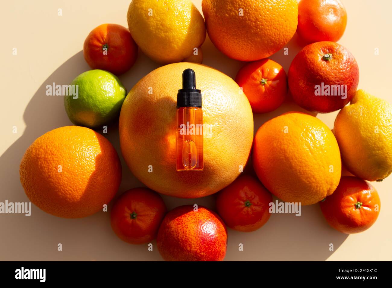 Siero di vitamina C in una bottiglia cosmetica con un contagocce su un set di agrumi. Arancio, pompelmo, lime, mandarino, limone. Cosmetici biologici SPA con olio d'arancia Foto Stock