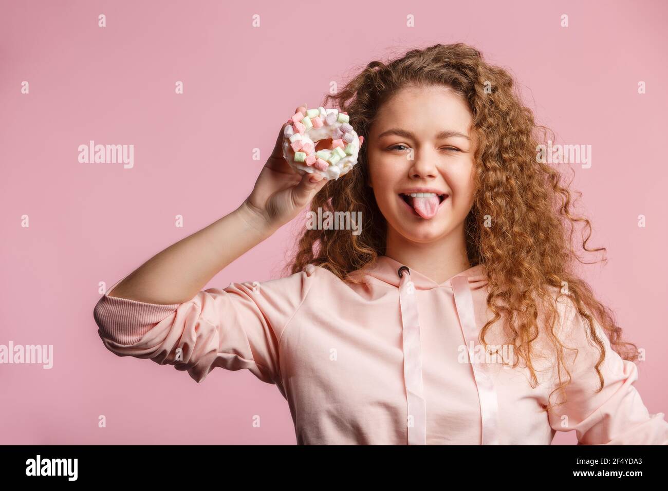 Giovane bella ragazza che tiene una ciambella rosa con marshmallows. Foto Stock