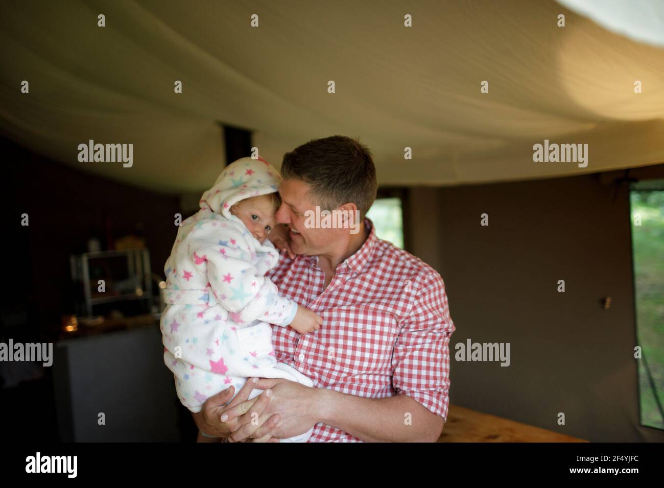 Padre che tiene la figlia carina in accappatoio in yurt Foto Stock