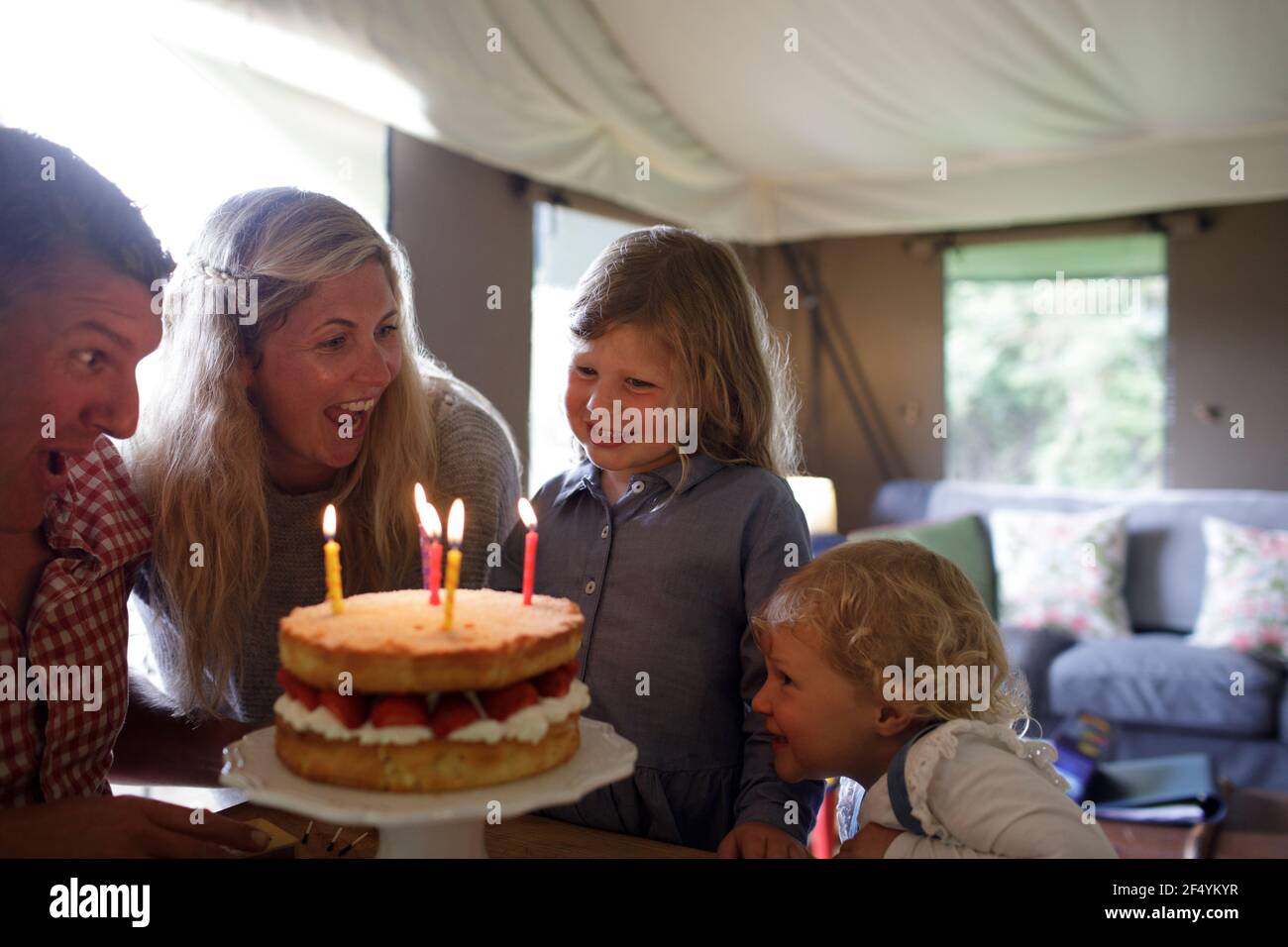 Felice ragazza che festeggia il compleanno con la famiglia e torta di fragole Foto Stock