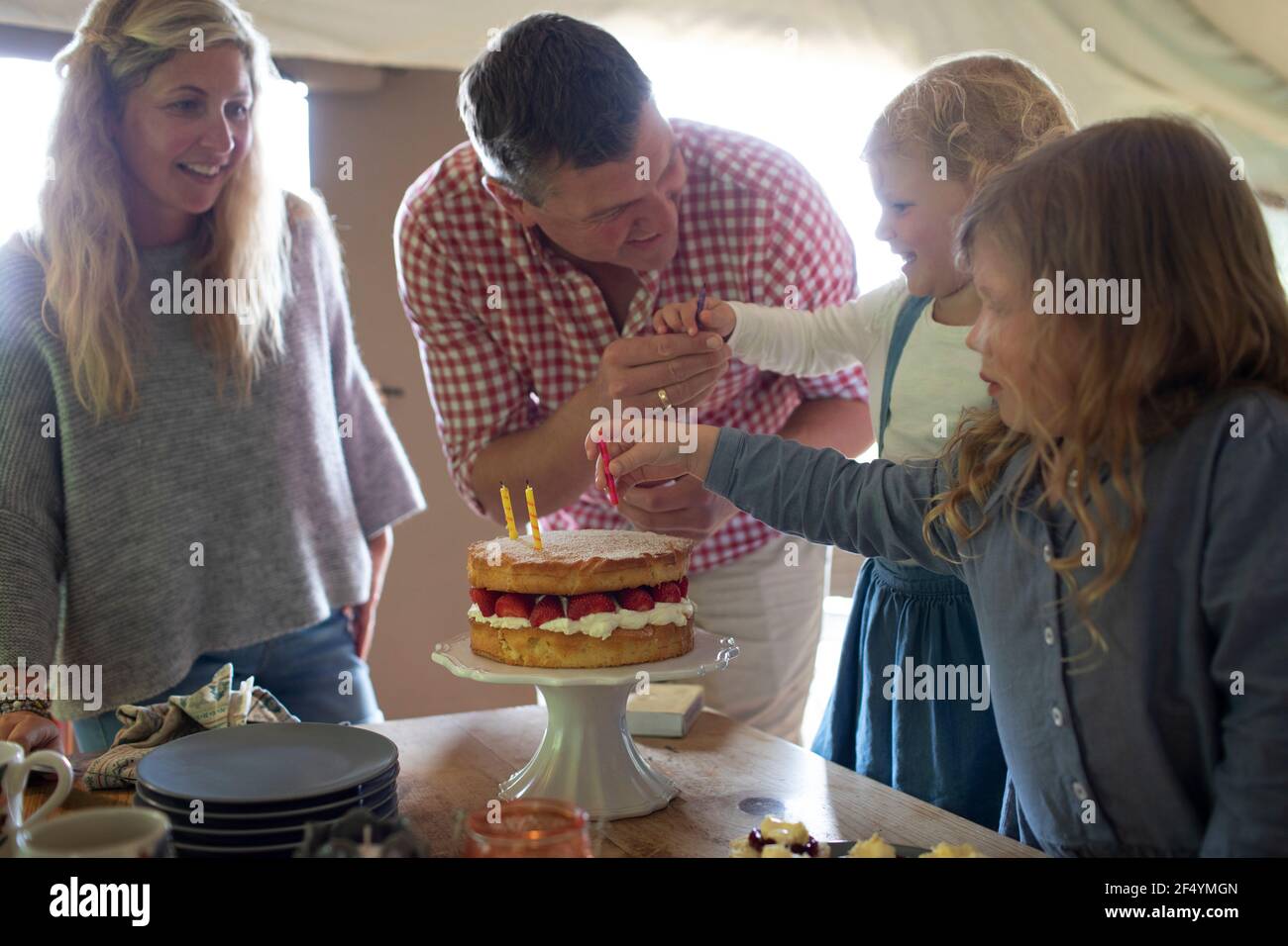 La famiglia festeggia il compleanno con torta di fragole e candele Foto Stock