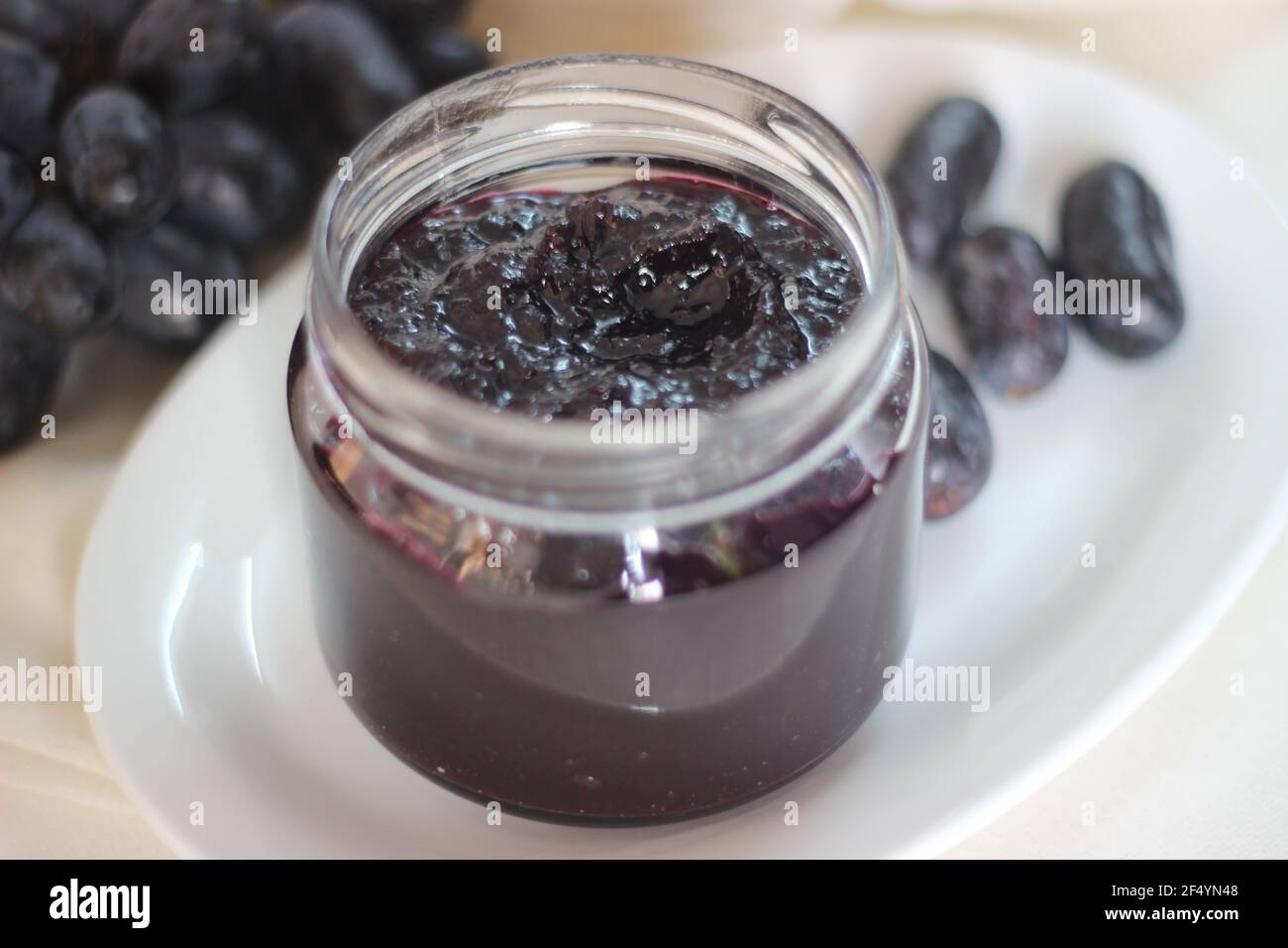 Marmellata d'uva fatta in casa con tre ingredienti, uva nera senza semi, zucchero e succo di lime. Scatto su sfondo bianco Foto Stock