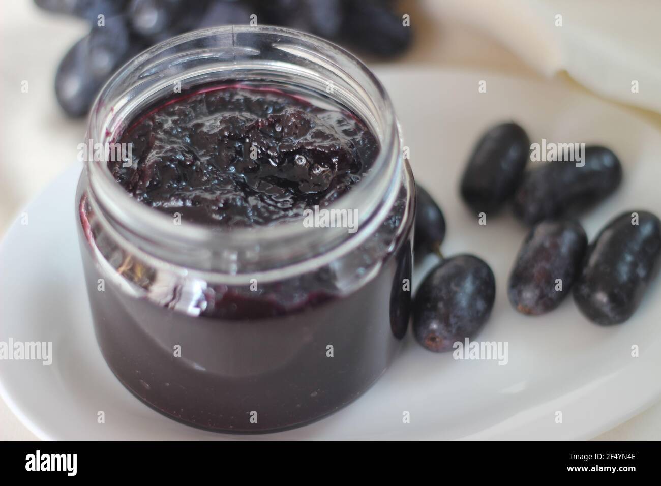 Marmellata d'uva fatta in casa con tre ingredienti, uva nera senza semi, zucchero e succo di lime. Scatto su sfondo bianco Foto Stock