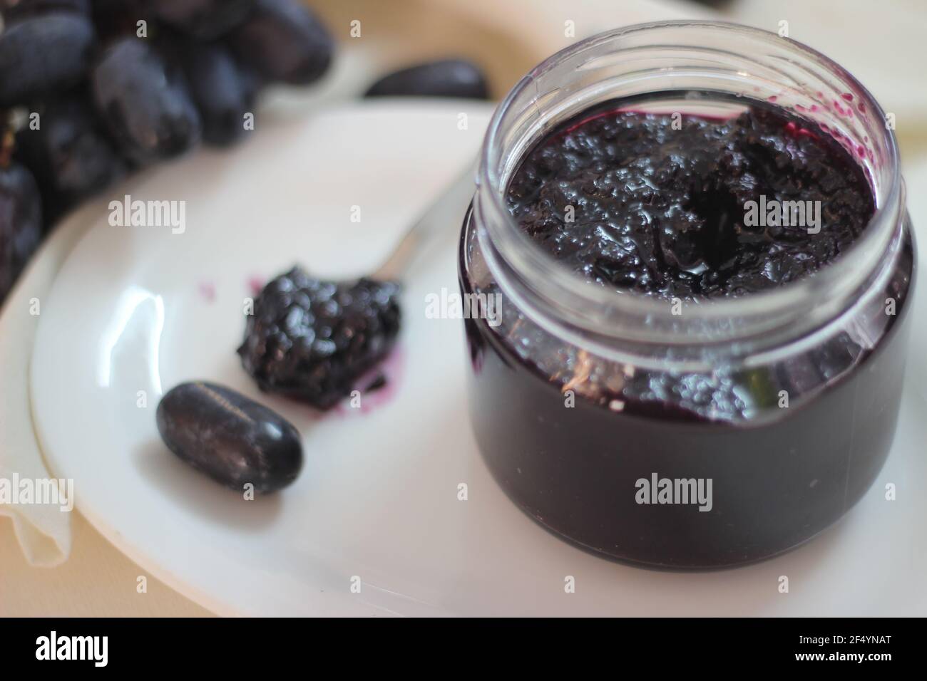 Marmellata d'uva fatta in casa con tre ingredienti, uva nera senza semi, zucchero e succo di lime. Scatto su sfondo bianco Foto Stock