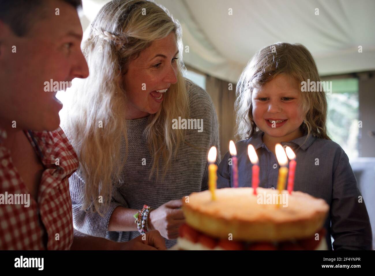 Felice figlia che festeggia il compleanno con la famiglia e torta con le candele Foto Stock