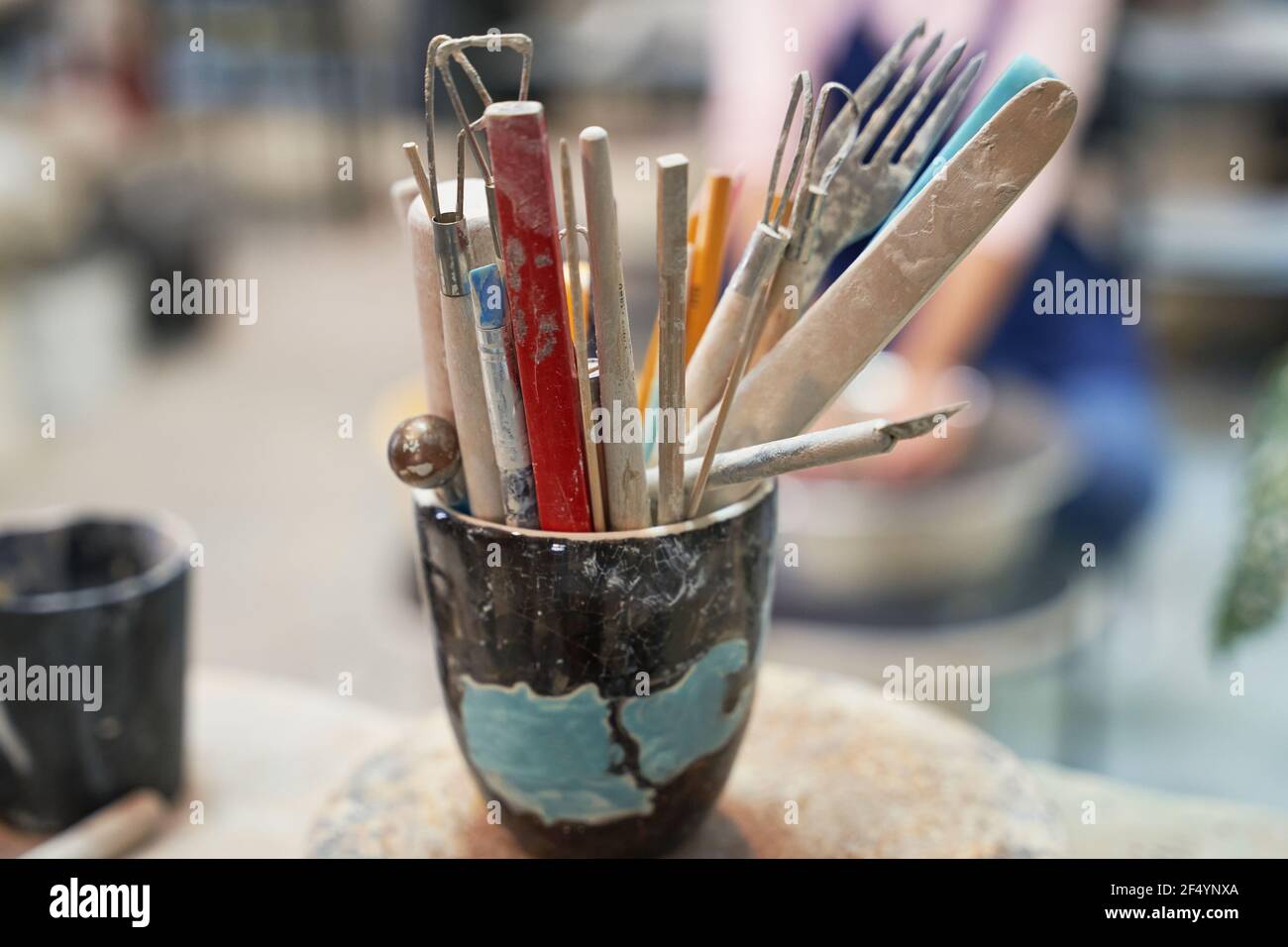 Ceramica. Primo piano di vasetto con utensili, spazzole per la creazione di ceramiche in argilla fatte a mano in officina Foto Stock