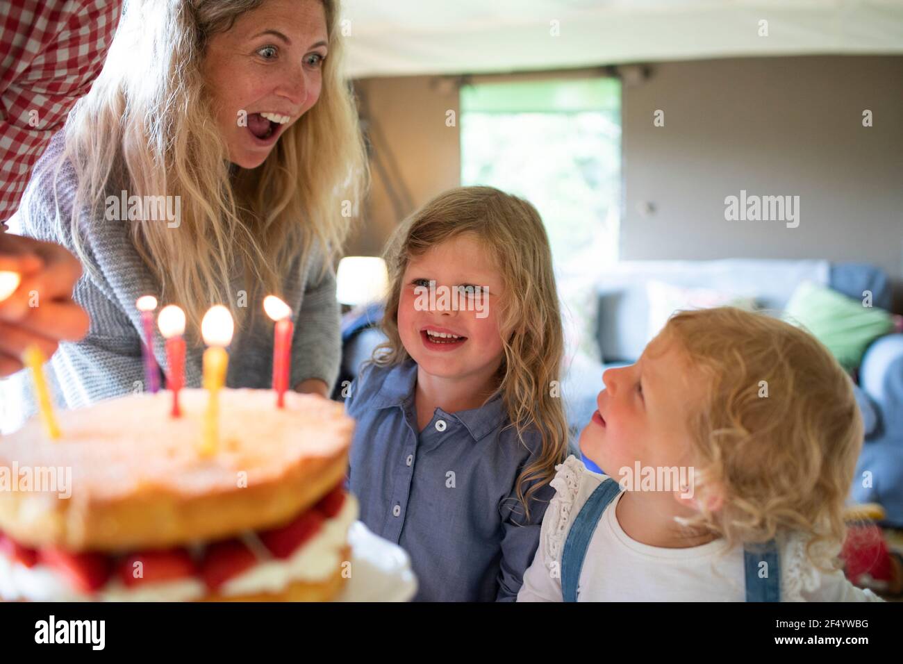 Felice madre e figlie che festeggiano il compleanno con torta e candele Foto Stock