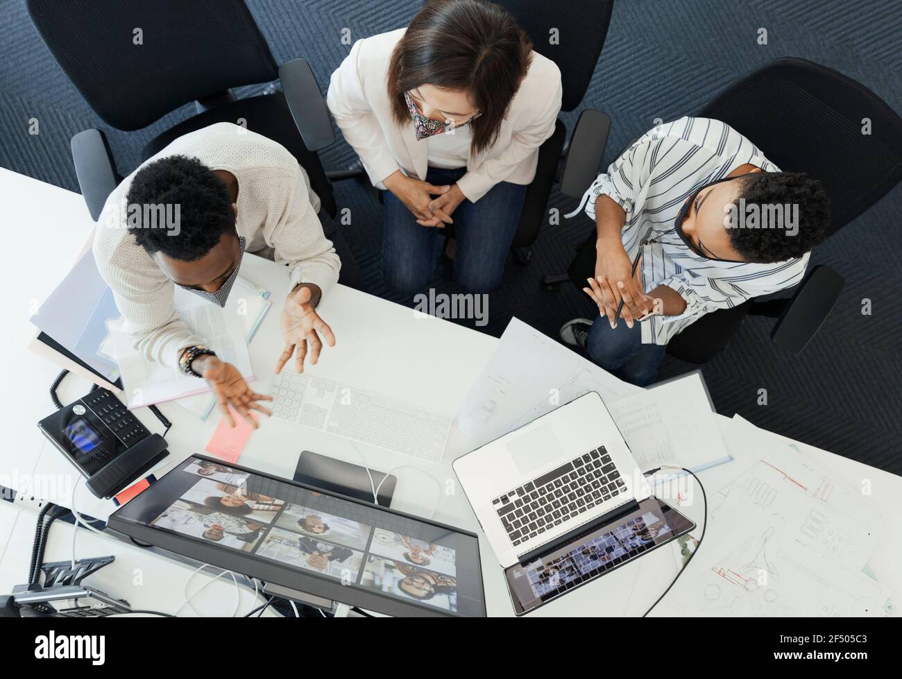 Uomini d'affari in maschere di faccia videoconferenza al computer dell'ufficio Foto Stock