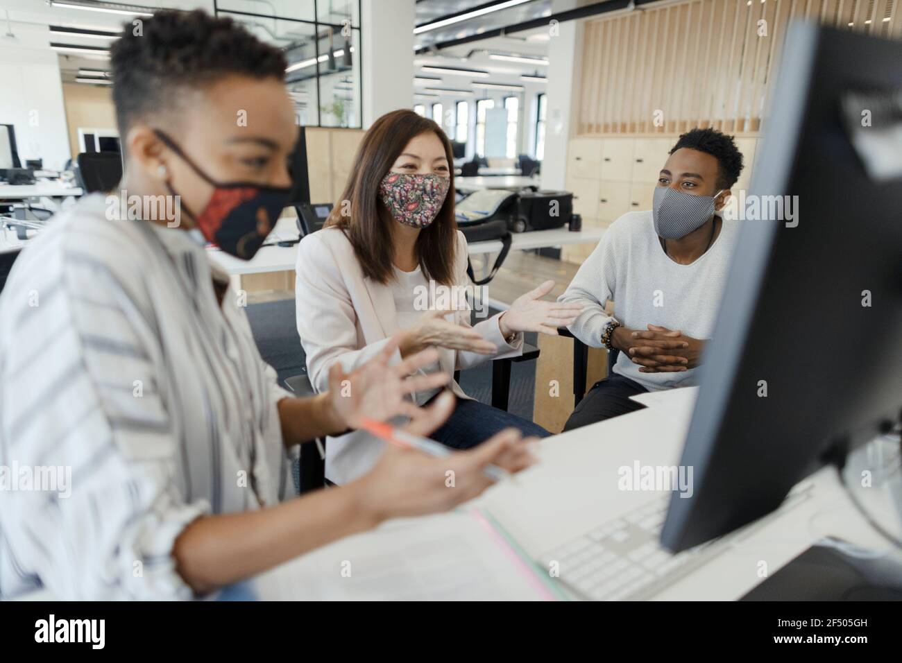 Uomini d'affari in maschere di faccia videoconferenza al computer dell'ufficio Foto Stock