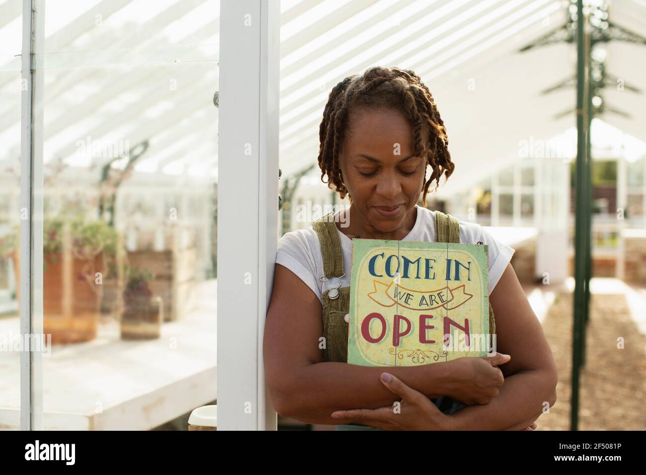 Ritratto donna giardino proprietario centro con segno aperto in serra Foto Stock