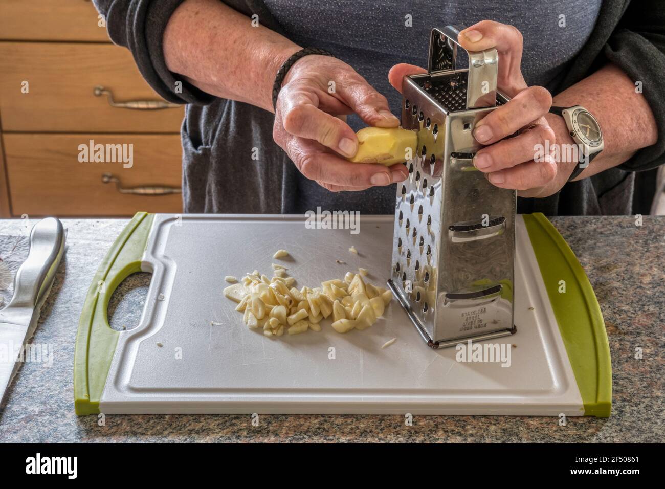 Donna grattugiare zenzero di radice per fare chutney. Foto Stock