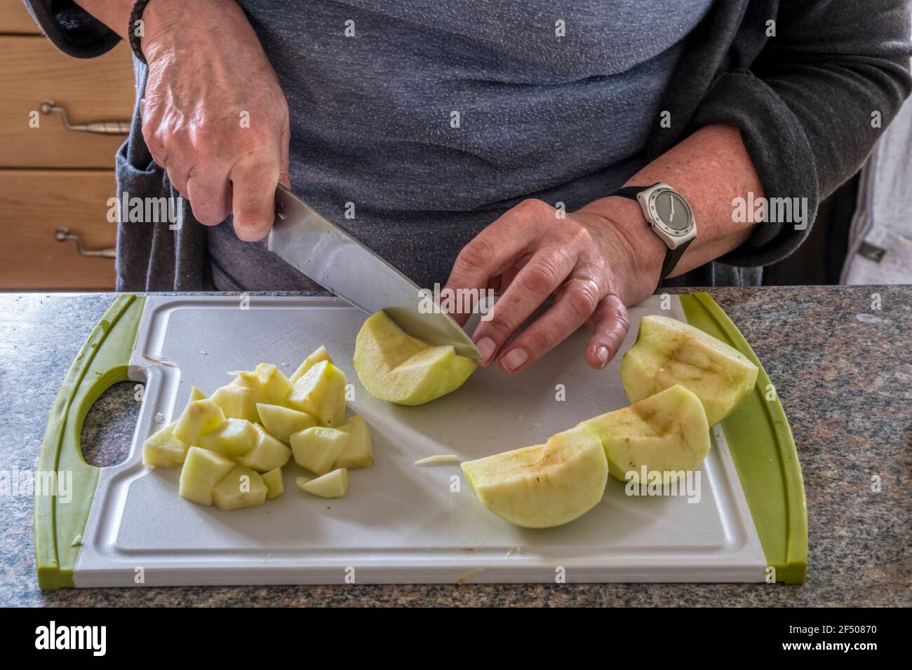 Donna che trita le mele da cucina per fare chutney. Foto Stock