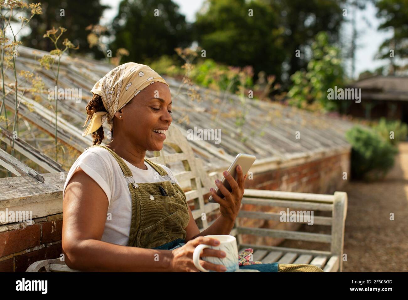 Donna pianta proprietario vivaio godendo pausa caffè con smartphone Foto Stock