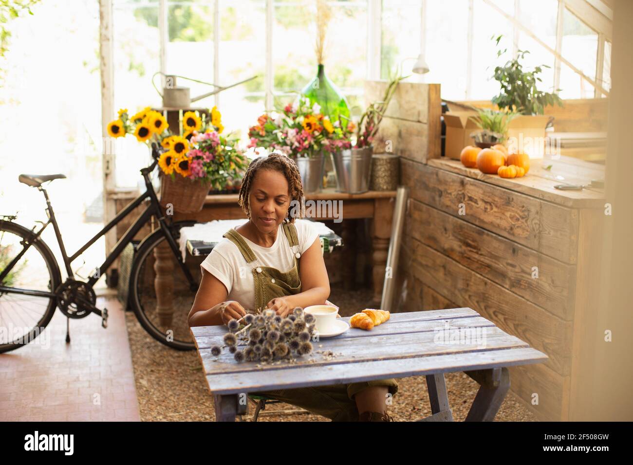 Fiorista femminile con fiori secchi che prende pausa caffè in fiore negozio Foto Stock