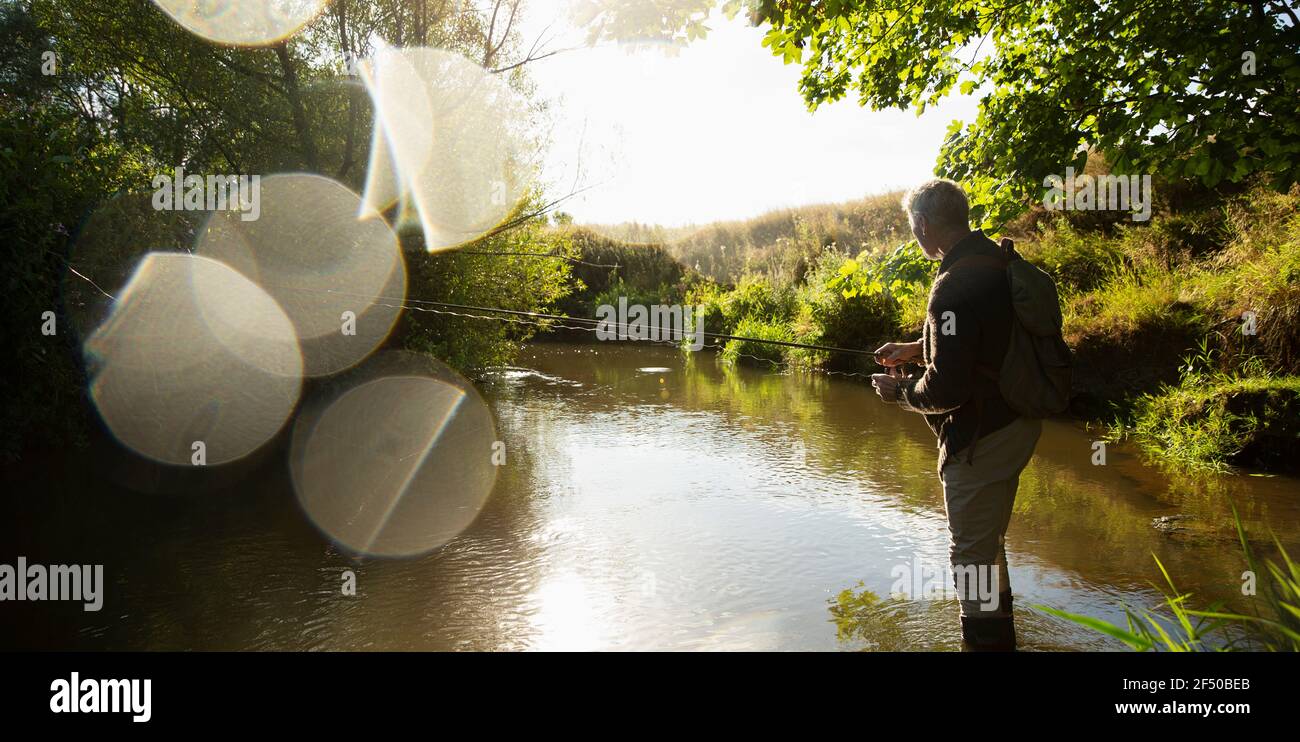 L'uomo pesca a mosca sul fiume idilliaco e soleggiato Foto Stock
