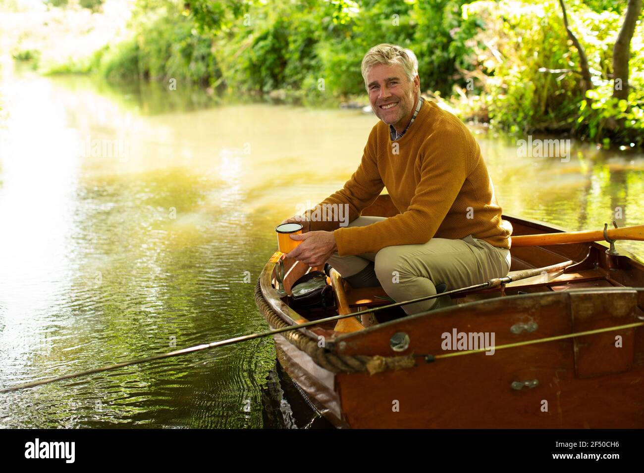 Ritratto uomo felice con caffè mosca pesca in barca su fiume Foto Stock