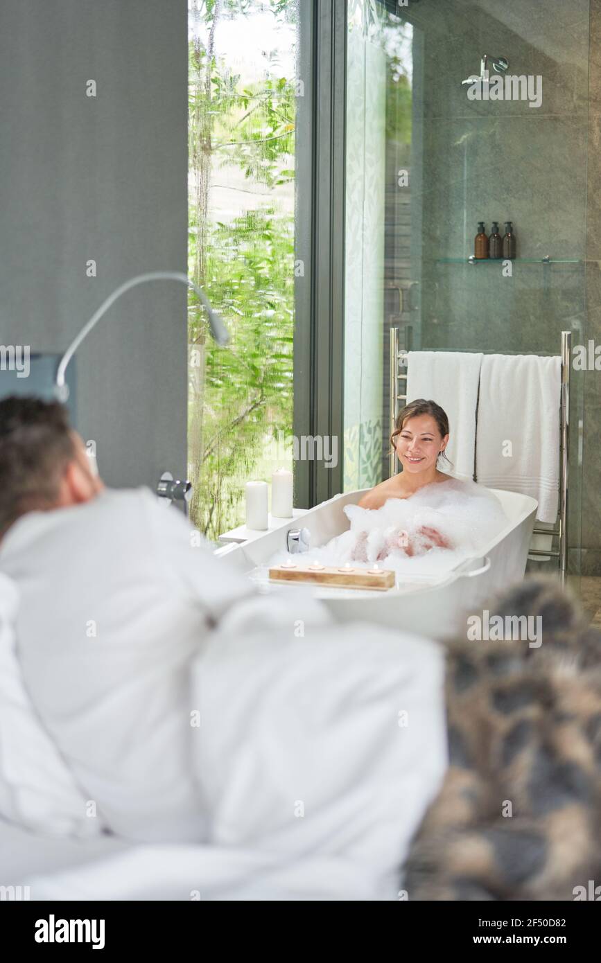 Coppia che prende bagno e posa in letto in lusso moderno camera d'albergo Foto Stock