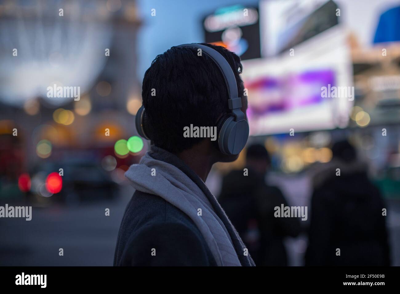 Giovane donna in cuffia sulla strada della città di notte Foto Stock