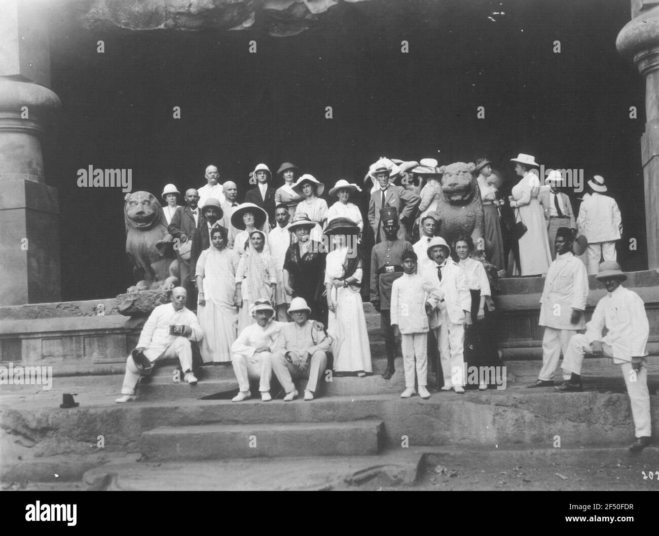 Elefanta, India. Shiva tempio di grotte di roccia. Uno degli ingressi con i turisti di Hapag sulla scala aperta con sculture di leoni fiancheggianti Foto Stock