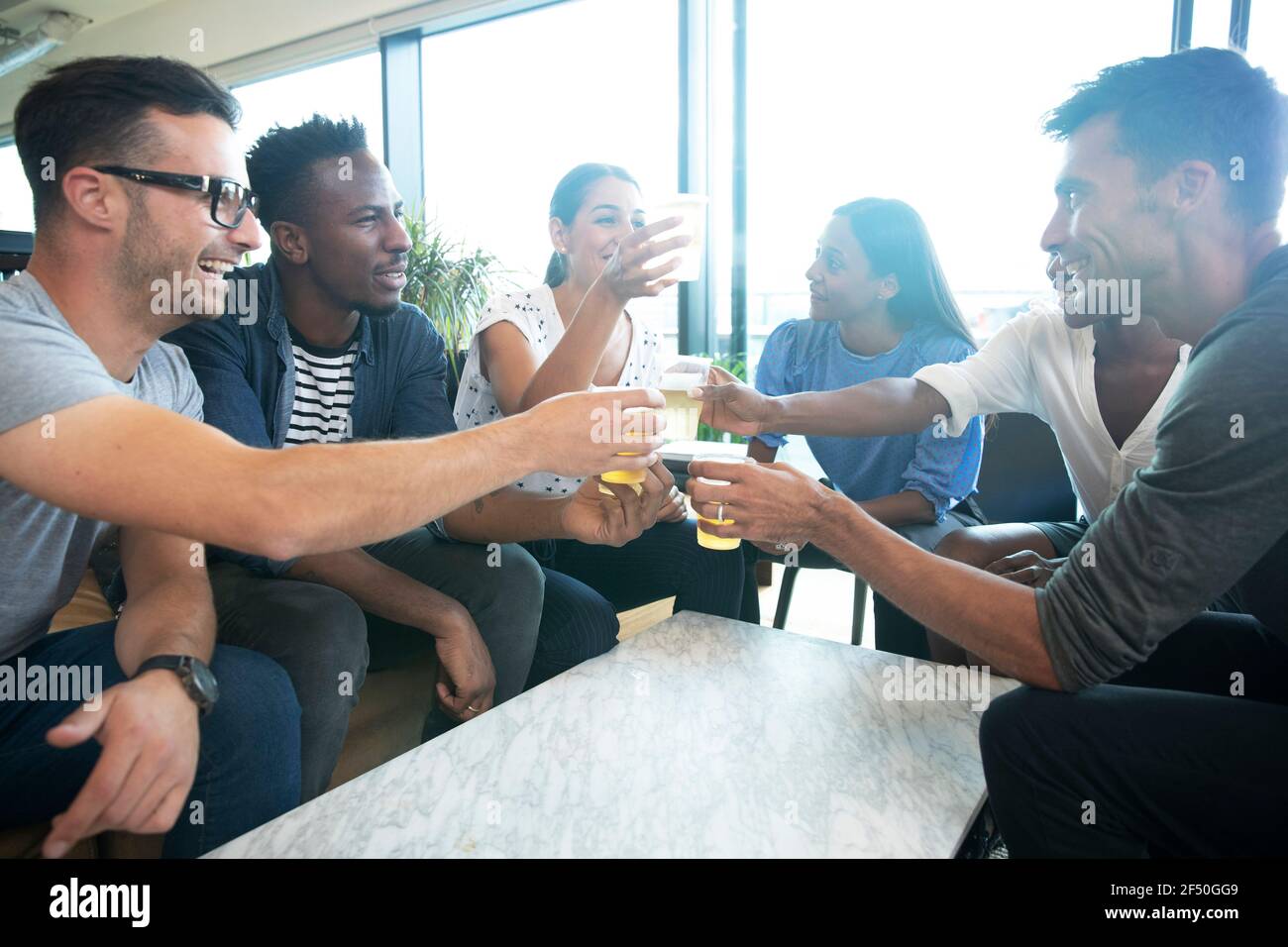 Diversi gruppi di uomini d'affari che gustano birre in ufficio Foto Stock