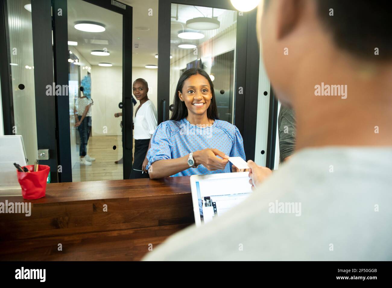 Donna d'affari felice con carta d'identità che effettua il check-in alla reception dell'ufficio scrivania Foto Stock