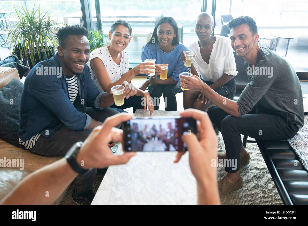 Uomo POV con smartphone fotografando amici bere birre Foto Stock