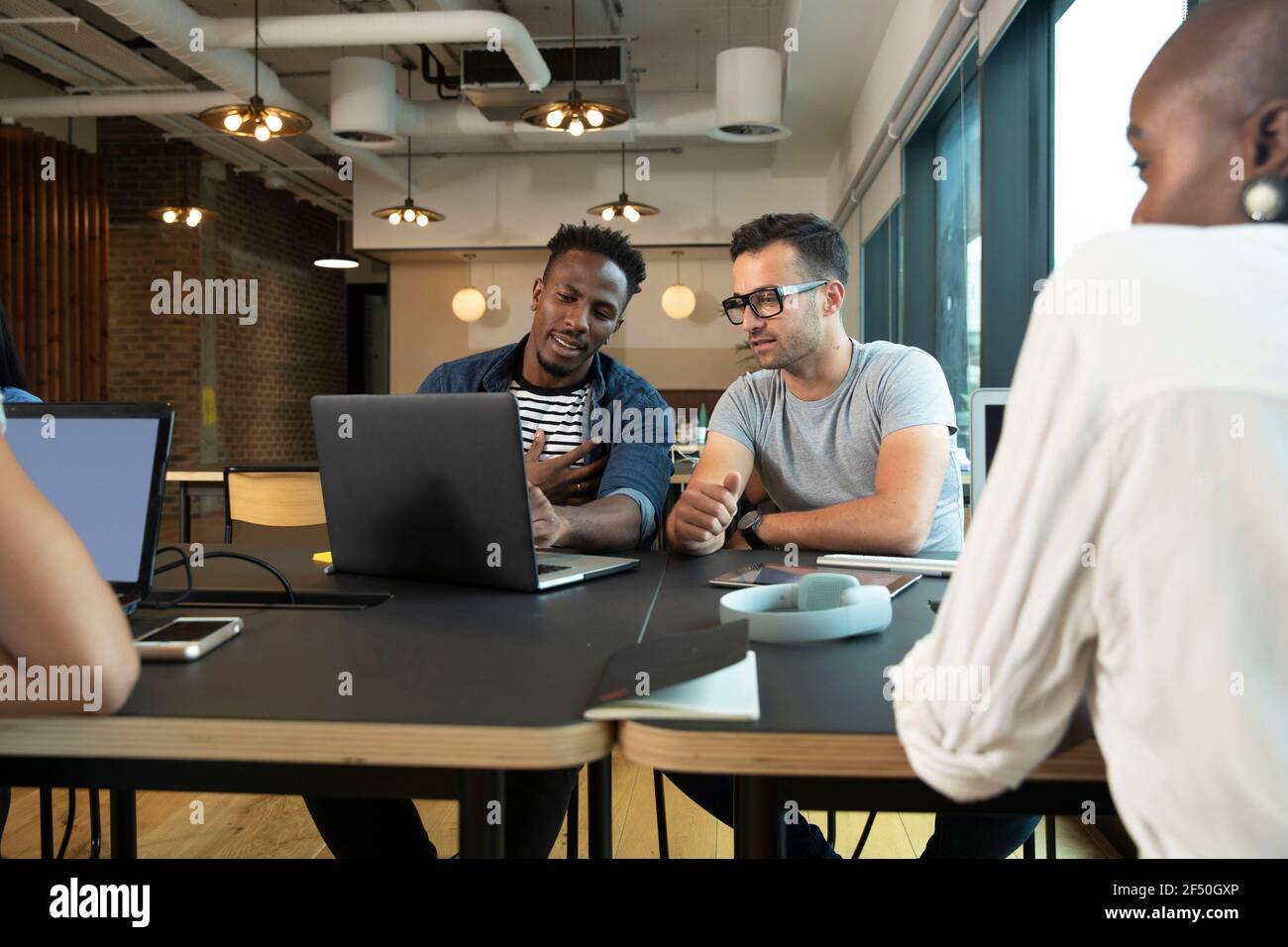 Uomini d'affari che si riunono al computer portatile in ufficio Foto Stock