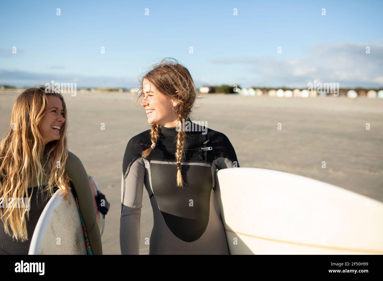 Felici giovani surfisti che portano tavole da surf sulla spiaggia soleggiata Foto Stock
