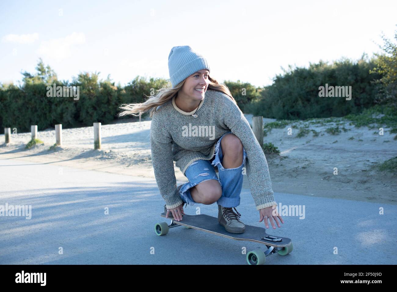 Spensierata giovane donna skateboarding sul sentiero della spiaggia Foto Stock