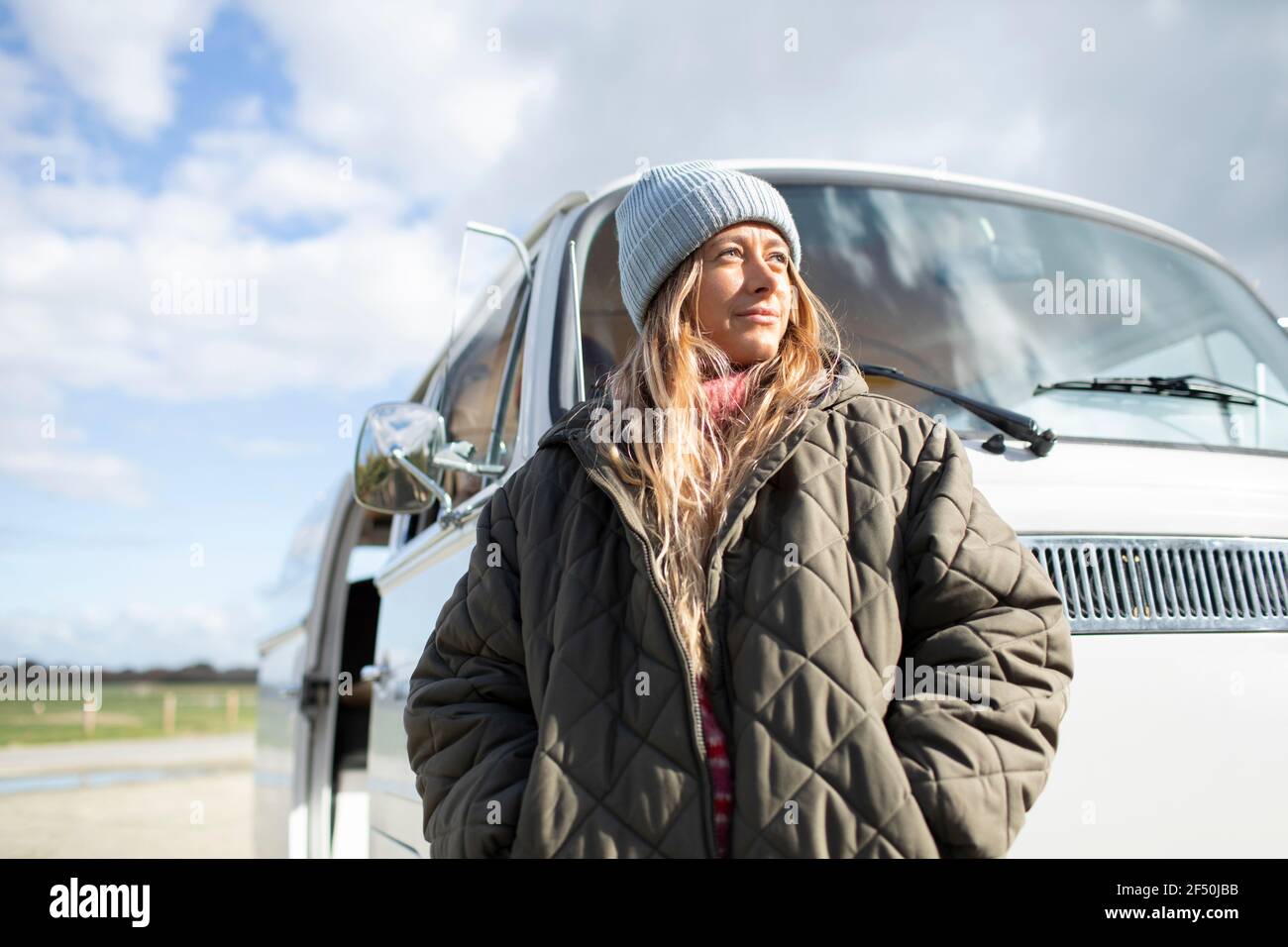 Ritratto giovane donna sicura in cappotto fuori furgone soleggiato Foto Stock
