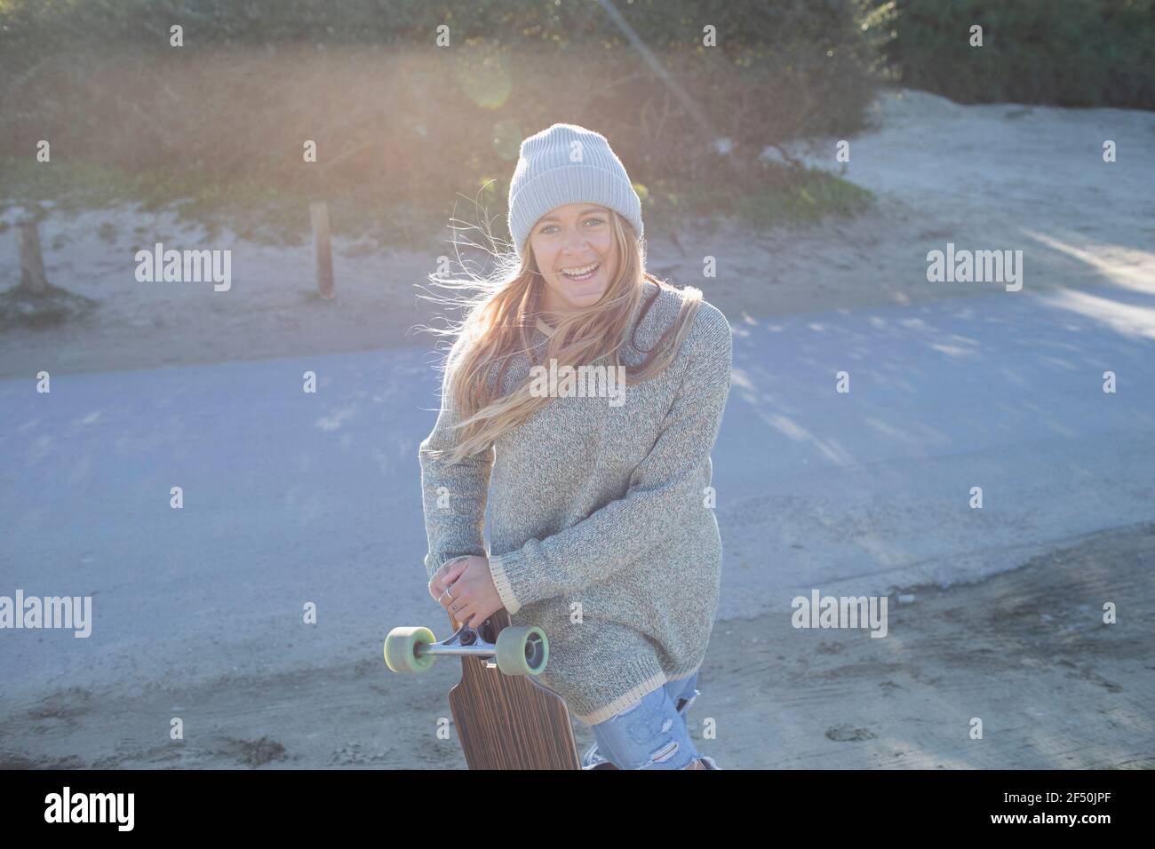 Ritratto giovane donna sicura con tavola da surf sulla spiaggia soleggiata Foto Stock