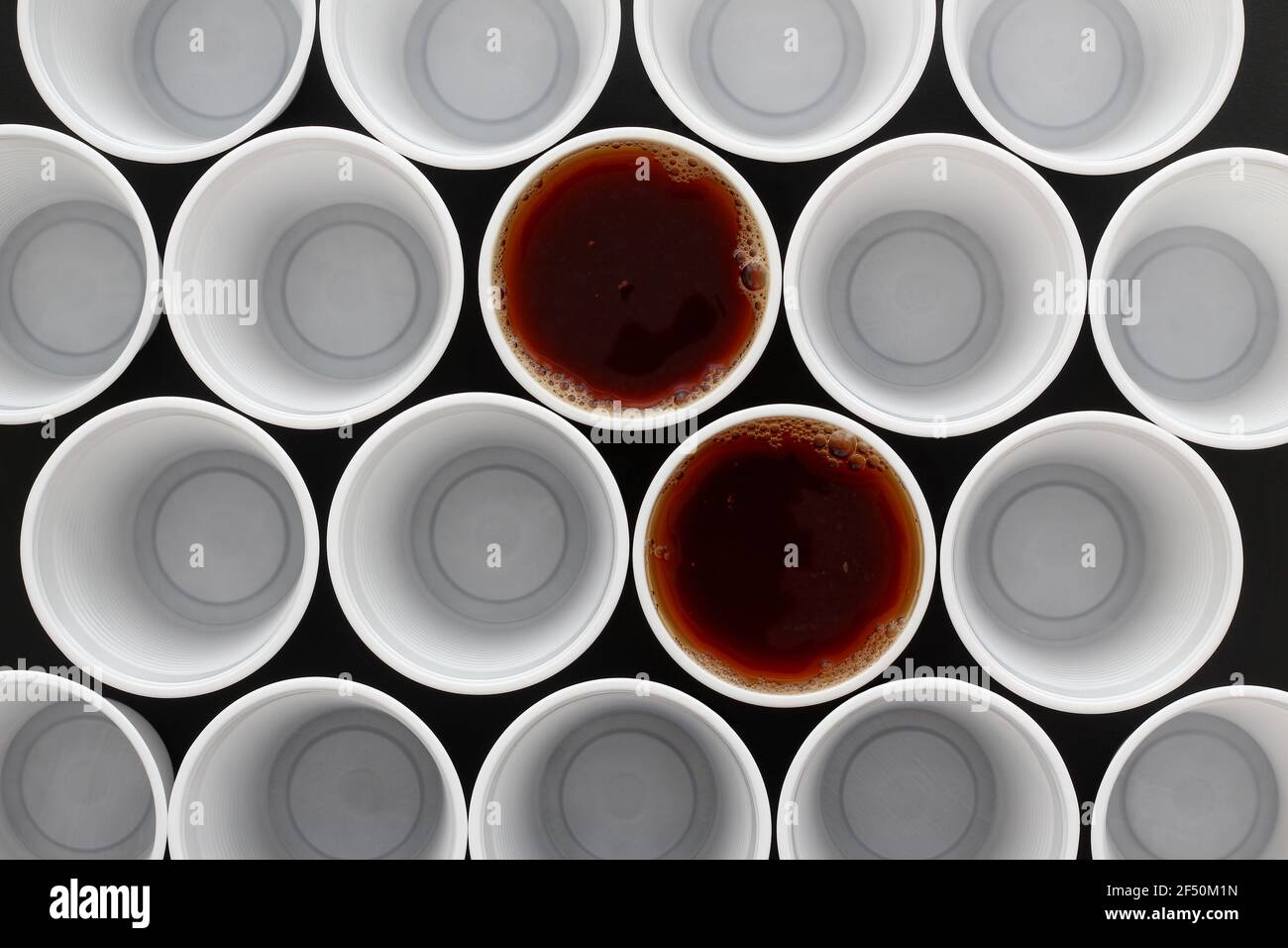 Due tè nero in tazze monouso in plastica insieme a molte altre tazze, vista dall'alto. Foto Stock