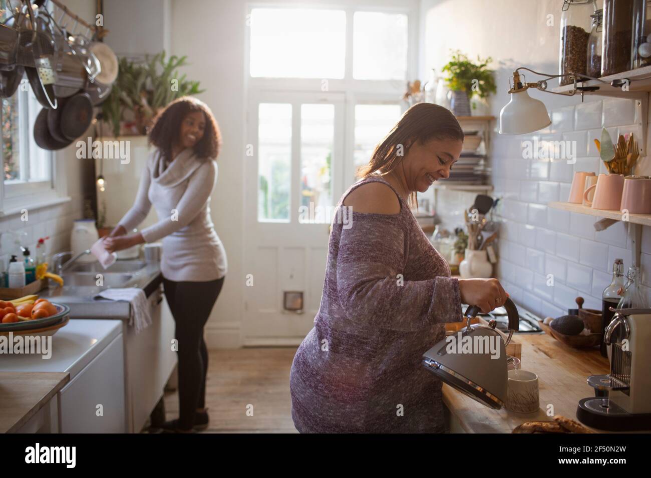 Madre e figlia che fanno i piatti e la preparazione del tè in cucina Foto Stock