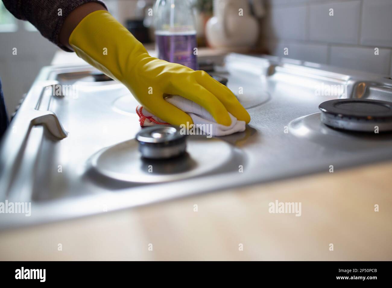 Primo piano donna in guanti di gomma che pulisce stufa da cucina con rag Foto Stock