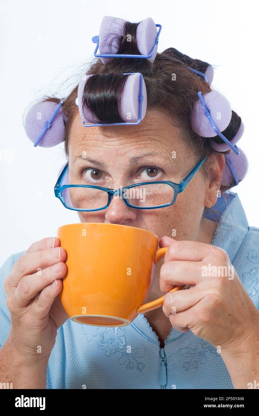 Colpo verticale di una donna matura con arricciacapelli che beve caffè. Questa è un'immagine rivista. Foto Stock