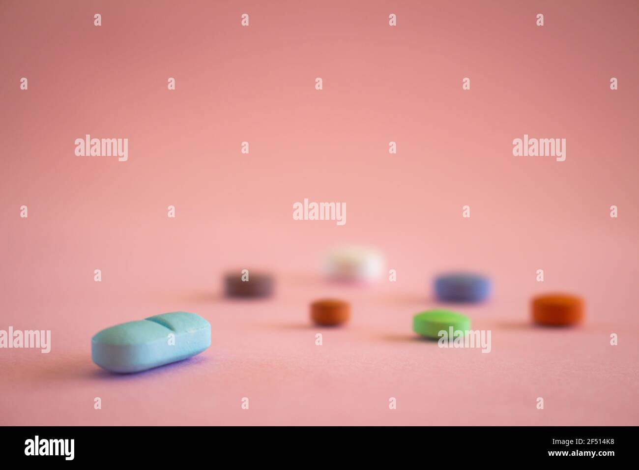 Farmaci sotto forma di pillole colorate su uno sfondo rosa neutro. Concetto medico con spazio libero di copia. Messa a fuoco selettiva. Foto Stock