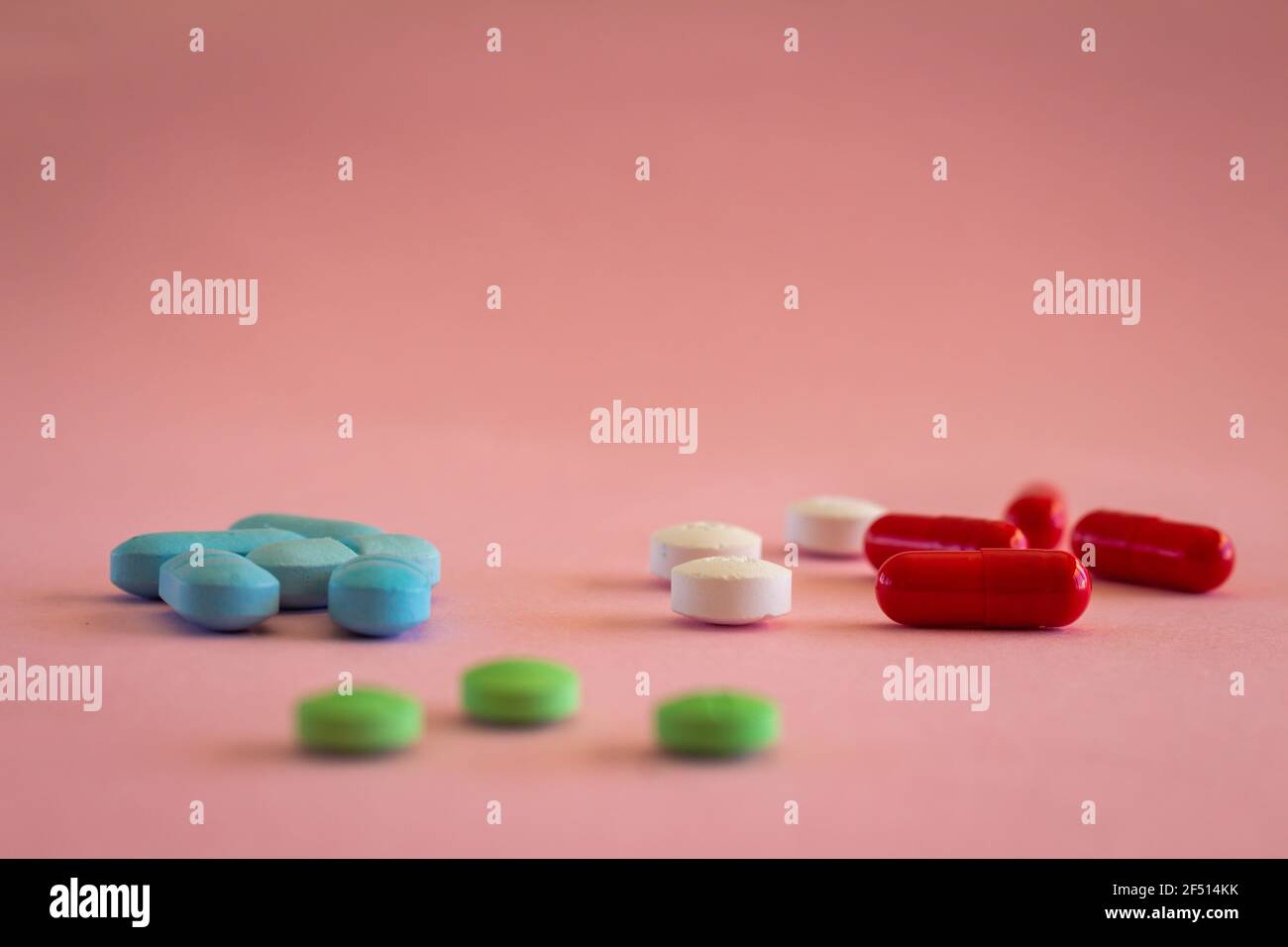 Farmaci sotto forma di pillole colorate su uno sfondo rosa neutro. Concetto medico con spazio libero di copia. Messa a fuoco selettiva. Foto Stock