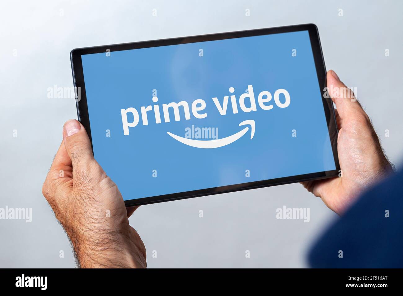 Uomo che tiene un tablet con il logo del servizio di streaming video principale sullo schermo. Foto Stock