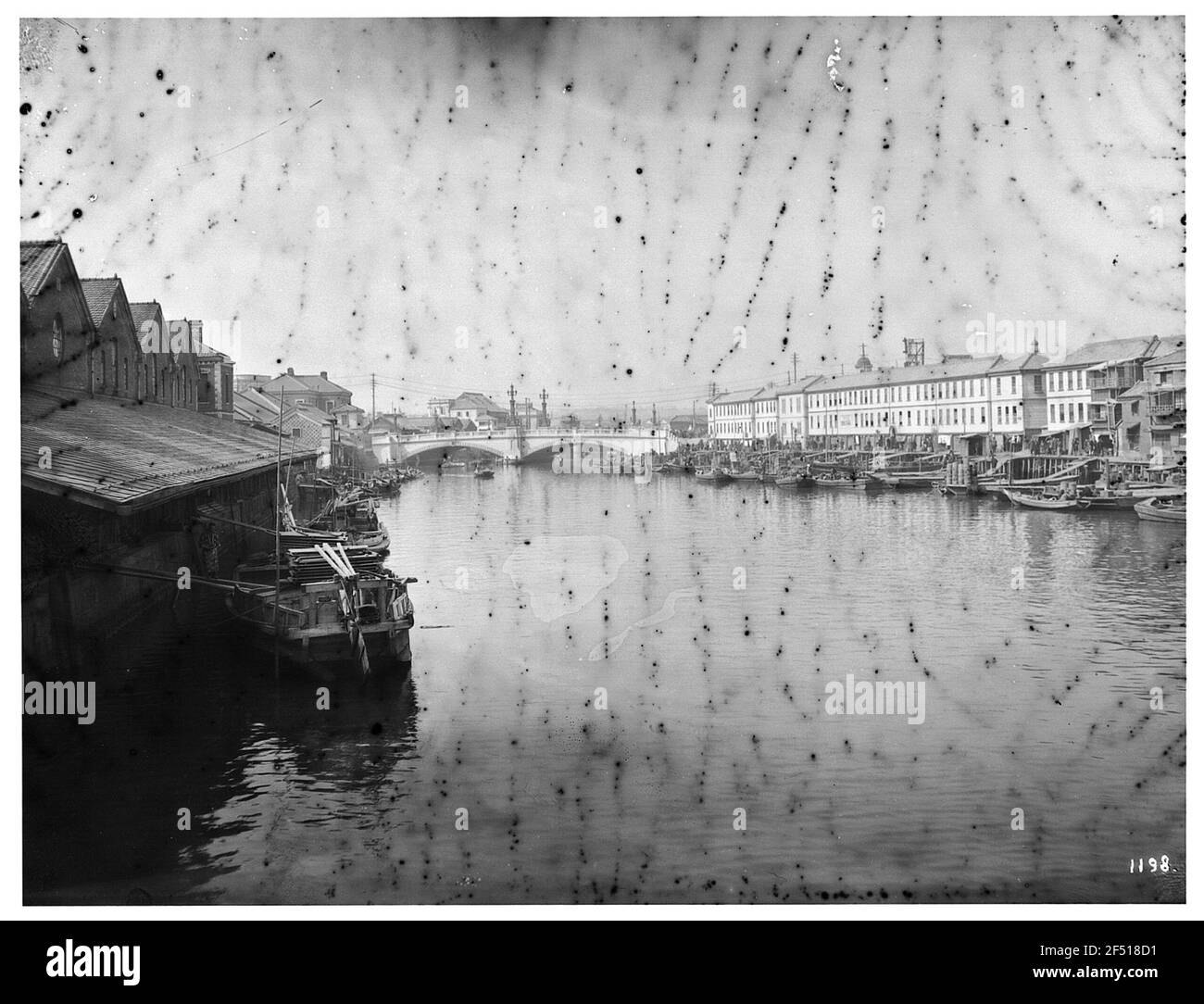 Tokyo, Giappone. Canale con entrambi i lati di sponde costruite, vi ormeggi con numerose chiatte, sullo sfondo doppio-boggy ponte di strada massiccia Foto Stock