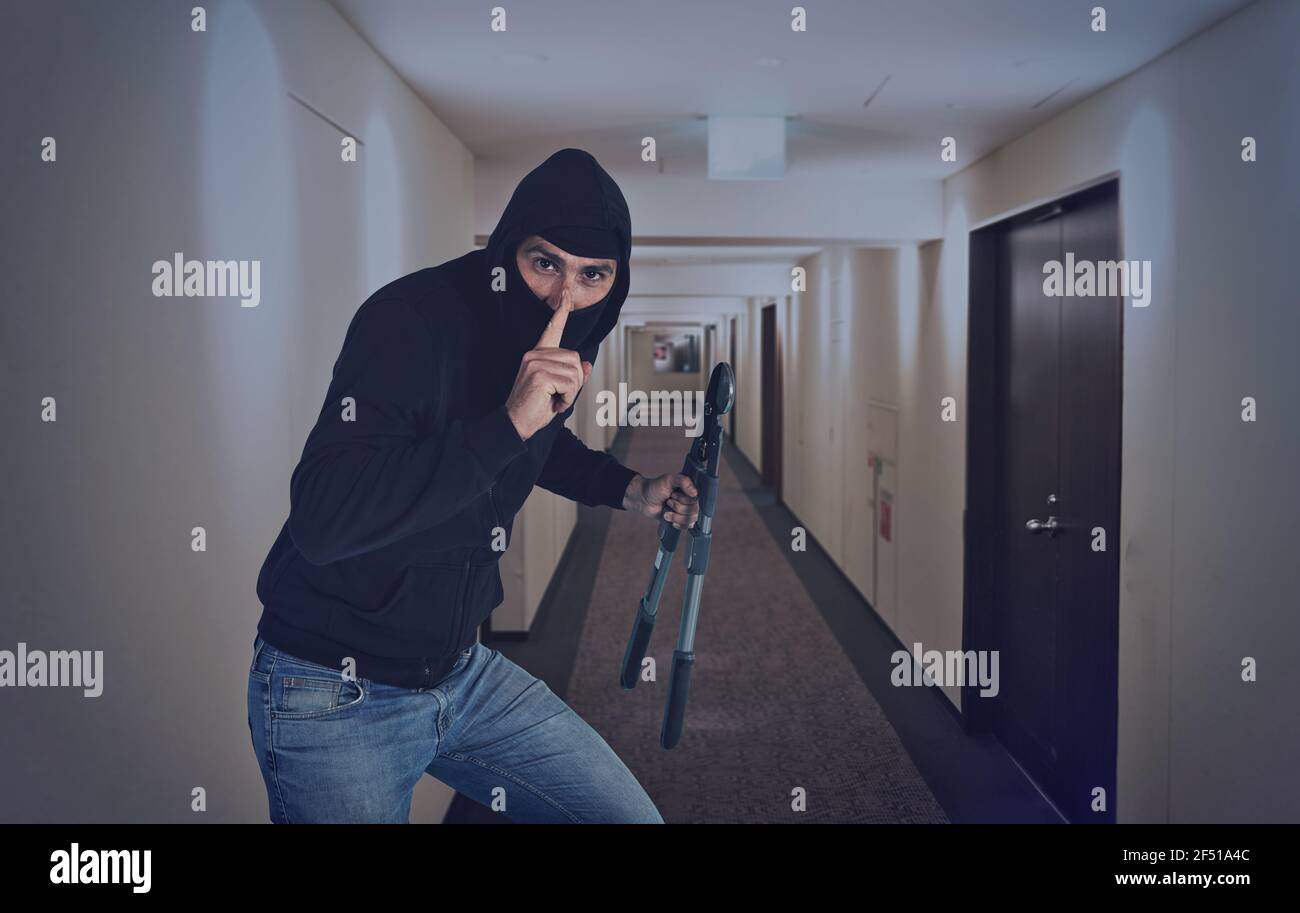 Ladro con balaclava agisce in silenzio per rubare appartamenti con tagliafili in mano Foto Stock
