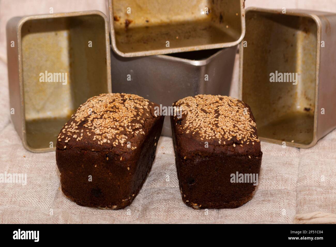 Pane di segala da dessert con uvetta e noci in pasta, cosparso di semi di sesamo e forme per cuocere il pane. Cottura fatta in casa Foto Stock