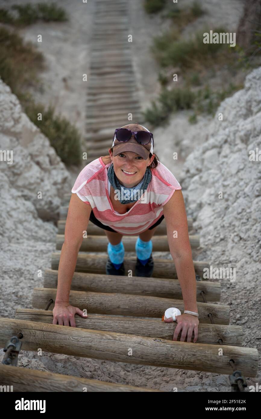 Happy Woman sale Log ladder su ripida pendio Foto Stock