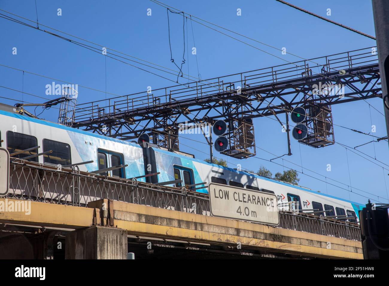 Il treno di Melbourne passa i segnali ferroviari sospesi su un gantry, Victoria, Australia Foto Stock