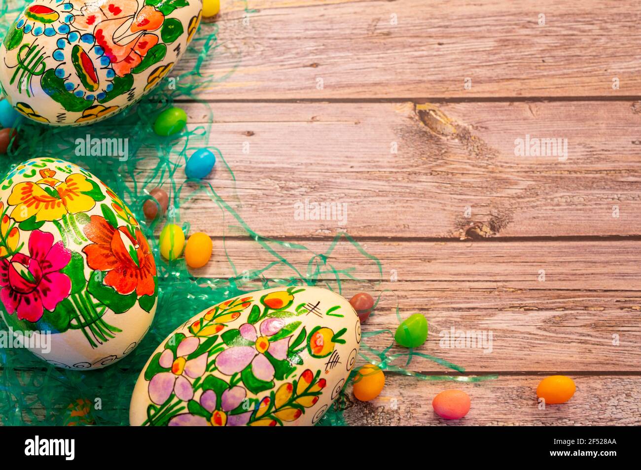 uova decorate e fagioli di gelatina su sfondo di legno Foto Stock