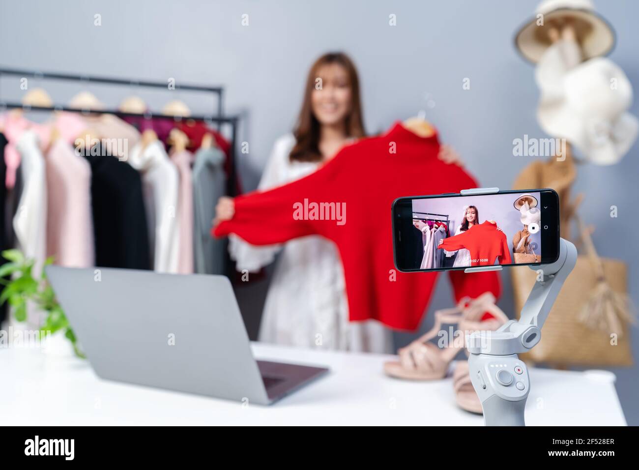 giovane donna che vende i vestiti in linea con lo streaming dal vivo dello smartphone, commercio elettronico in linea di affari a casa Foto Stock