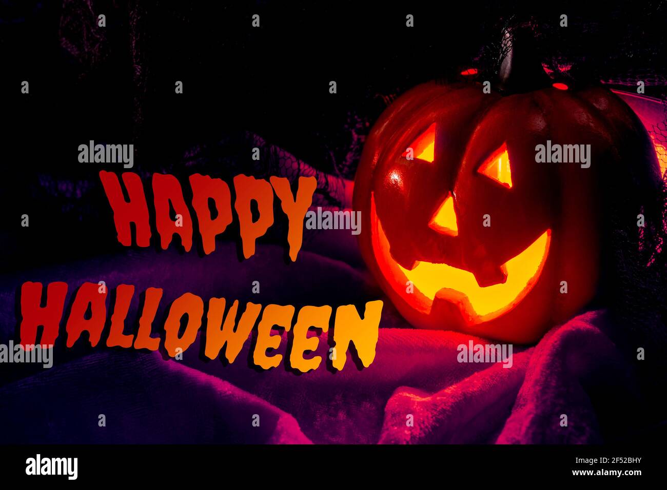 Halloween festa e vacanze autunno concetto con jack o'lantern illuminato zucca con occhi spaventosi e luminosi e sorridi che illuminano il buio di notte su velluto Foto Stock