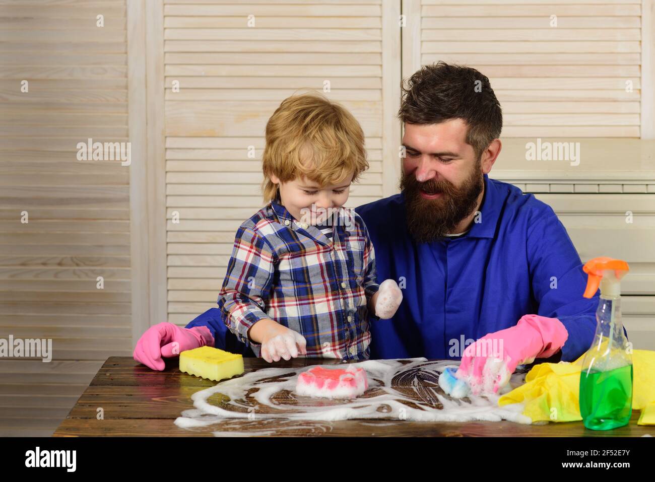 Padre sta insegnando a un figlio una pulizia. Buona famiglia pulisce la camera. Papà e bambina sono spolverati, lavando il pavimento e spray. Foto Stock