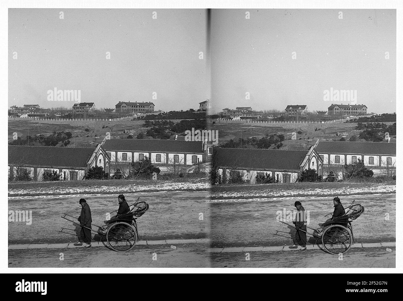 Tsingtau / Cina: Riksha contro la rivista imperiale. Riksha con i clienti nativi sulla parte anteriore contro le case con la rivista imperiale Foto Stock